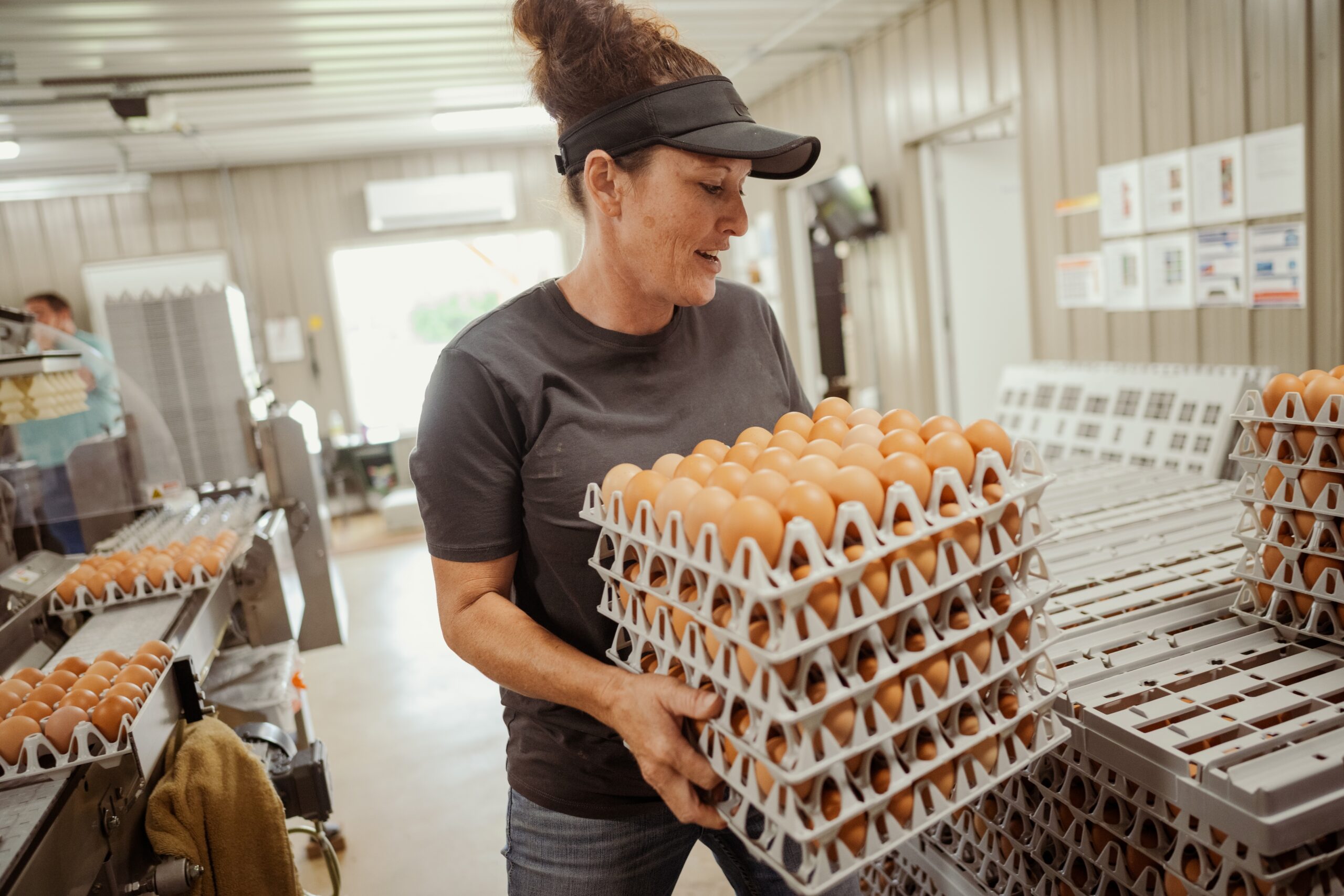Woman holds stack of eggs in crates